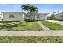 Charming single-story home featuring a well-maintained lawn and complemented by mature palm trees at 21923 Cellini Ave, Port Charlotte, FL 33952