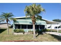 Charming single-story home with awnings, manicured landscaping, and mature palm trees at 258 Palm Harbor Dr, North Port, FL 34287