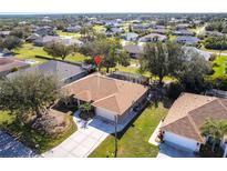 Expansive aerial view of the tan single-story home with an attached garage and screened-in patio at 27199 Punta Cabello Ct, Punta Gorda, FL 33983