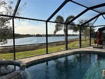 A screened-in pool overlooks the scenic lake in this backyard oasis with a spa and waterfall feature at 7049 Waterford Pkwy, Punta Gorda, FL 33950