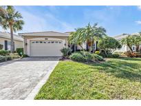 Charming home with a tile roof, paver driveway, lush landscaping, and a well-manicured lawn at 1620 Lancashire Dr, Venice, FL 34293