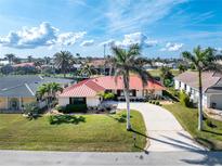 Inviting single-story home with a red roof, lush lawn and mature palms at 35 Sabal Dr, Punta Gorda, FL 33950