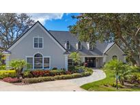 Elegant home showcasing meticulous landscaping, a gray tile roof, arched windows and a welcoming, paved walkway at 4 Saint Martin Cir, Englewood, FL 34223