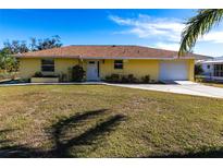 Charming one-story yellow home with a well-manicured lawn and driveway leading to an attached garage at 8029 Roy Dr, Punta Gorda, FL 33982