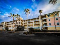 Brightly painted three story condo building with multiple units and external staircases, surrounded by palm trees at 8403 Placida Rd # 408, Placida, FL 33946