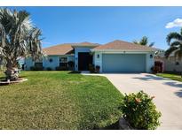 Charming single-story home with a well-manicured lawn, palm trees, and a two-car garage, showcasing curb appeal at 9175 Melody Cir, Port Charlotte, FL 33981