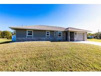 Charming single-story home showcasing a gray stucco exterior, stone accents, and a well-manicured front yard at 11176 3Rd Ave, Punta Gorda, FL 33955