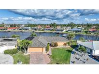 Waterfront home with a tile roof, attached garage, and tropical landscaping, located on a canal with boat access at 1200 Winward Ct, Punta Gorda, FL 33950