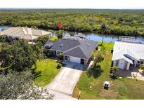 Charming single-story home with lush lawn, mature trees, and a two-car garage on a waterfront property at 19179 Aviation Ct, Port Charlotte, FL 33948