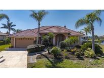 Charming single-story home with a red tile roof, lush landscaping, and a two-car garage at 237 Freeport Ct, Punta Gorda, FL 33950