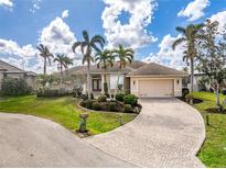 Charming home featuring a tile roof, brick driveway, and beautifully manicured landscaping with palm trees at 1217 Bobwhite Court, Punta Gorda, FL 33950
