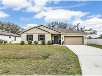 Charming single-story home with beige stucco, dark shutters, well-maintained landscaping, and an attached two-car garage at 2822 Logsdon St, North Port, FL 34287