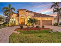 Stunning home exterior with tropical landscaping, barrel tile roof, and brick paved driveway at 3321 Tripoli Blvd, Punta Gorda, FL 33950