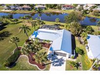 An aerial view showcases a property with a new metal roof, palm trees, and a pool with a screened enclosure at 483 Corrientes Cir, Punta Gorda, FL 33983