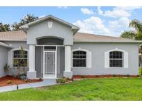 Charming front entrance with beautiful columns, arched window accents, and freshly manicured lawn at 5366 Dunsmuir Rd, North Port, FL 34288