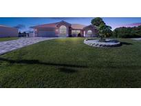Pink house with landscaped yard, driveway, and stone accents at dusk at 256 Coblentz St, Port Charlotte, FL 33954