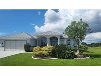 Single-story home with metal roof and landscaped yard at 15418 Alcove Cir, Port Charlotte, FL 33981