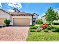 Charming home with a brick driveway, beige garage door, terra cotta roof, and lush landscaping at 26950 Pavin Dr, Englewood, FL 34223