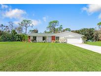 Single-story home with green roof, white exterior, and spacious lawn at 1115 Larchmont Dr, Englewood, FL 34223