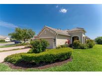 Tan two-car garage home with landscaping and paver driveway at 1384 Backspin Dr, Englewood, FL 34223