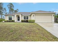 Tan house with a two-car garage and well-manicured lawn at 2236 Gascom St, North Port, FL 34288