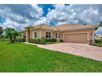 Tan house with tile roof, large driveway, and lush landscaping at 13104 Creekside Ln, Port Charlotte, FL 33953