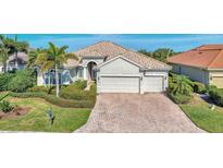 Tan two-story house with tile roof, large driveway, and lush landscaping at 13025 Cedar Creek Dr, Port Charlotte, FL 33953