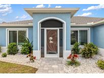 Charming light blue house with landscaped yard and three-car garage at 13838 Begonia Cir, Port Charlotte, FL 33981