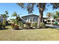 Single-wide manufactured home with landscaped yard and large tree at 6113 Partridge Ave, Englewood, FL 34224