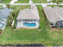 Aerial view of an enclosed pool surrounded by green grass and landscaping at 171 Medalist Rd, Rotonda West, FL 33947