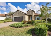 Tan house with brown garage door, blue front door, and landscaped yard at 26812 Pavin Dr, Englewood, FL 34223
