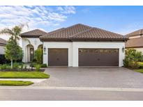 White one-story house with brown tile roof, two-car garage, and landscaped front yard at 26866 Weiskopf Dr, Englewood, FL 34223