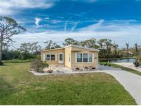 Tan mobile home with landscaped yard and waterfront view at 3302 Bluejay Ln, Englewood, FL 34224