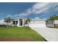 White two-story house with a three-car garage, and lush landscaping at 159 Colony Point Dr, Punta Gorda, FL 33950