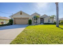 Tan one-story house with a two-car garage and well-manicured lawn at 80 Long Meadow Ln, Rotonda West, FL 33947