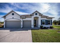 Two-story house with gray siding, two-car garage, and landscaped lawn at 8626 Agate St, Port Charlotte, FL 33981