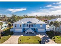 Two-story light blue house with white trim, metal roof, and a paved driveway at 9240 Pine Cove Dr, Englewood, FL 34224