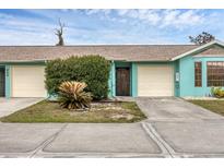Light teal exterior of home with attached garage and landscaping at 255 Boundary Blvd # 104, Rotonda West, FL 33947