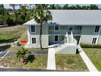 Two-story condo building with stairs, balconies, and lush landscaping at 8050 Memory Ln # 104, Rotonda West, FL 33947