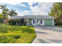 Cute single-story home with a green garage door and well-manicured lawn at 9261 Saint Catherine Ave, Englewood, FL 34224