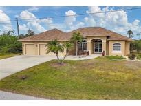 Tan house with three-car garage, palm trees, and a manicured lawn at 116 Hercules Dr, Rotonda West, FL 33947