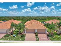 Aerial view of a community featuring villas with orange tile roofs and lush landscaping at 24028 Canterwood Way, Venice, FL 34293