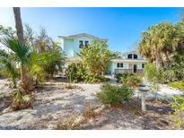 Light teal two-story house with palm trees and a garden at 7630 Manasota Key Rd, Englewood, FL 34223