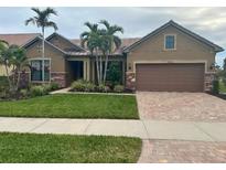 One-story home with a brown facade, brick driveway, and lush landscaping at 13639 Salinas St, Venice, FL 34293