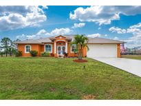 Attractive orange house with a large yard, two-car garage, and palm trees at 2194 Wenona Dr, North Port, FL 34288