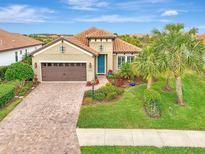 Tan house with brown garage door, landscaping, and palm trees at 26906 Weiskopf Dr, Englewood, FL 34223