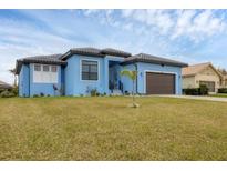 Beautiful light blue house with a brown garage door and nicely landscaped lawn at 4220 Cape Haze Dr, Placida, FL 33946