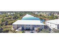 A beautiful aerial view of the condo building surrounded by a serene lake and lush greenery at 9700 Fiddlers Green Cir # 117, Rotonda West, FL 33947