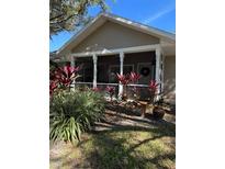 Tan one-story house with covered porch, lush landscaping, and mature trees at 1415 Winding Oak Dr, Port Charlotte, FL 33948