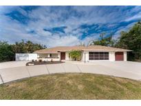 Single-story home with circular driveway, attached garage, and landscaped yard at 1600 Thomas St, Englewood, FL 34223